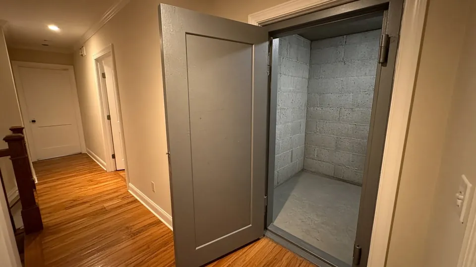 Interior tornado safe room with a heavy steel door inside a home